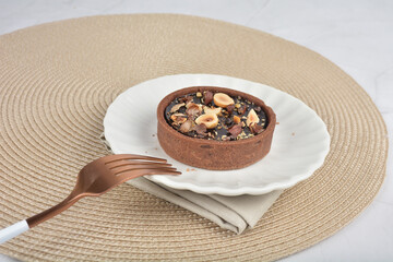 freshly handmade beautiful France rocher dark chocolate layer tart w mixed macadamia peanuts on white marble luxury background with bamboo decoration halal food dessert menu for cafe