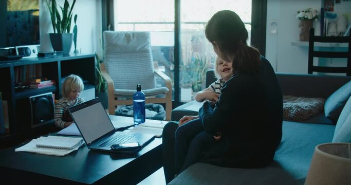 Freelancer woman work at home using laptop computer and take care of children