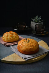 freshly handmade baked Macau crispy round polo bun bread w red bean paste on dark black luxury background with ceramic decoration halal food dessert menu for cafe