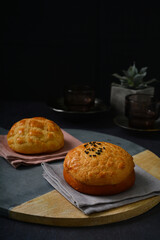 freshly handmade baked Macau crispy round polo bun bread w red bean paste on dark black luxury background with ceramic decoration halal food dessert menu for cafe