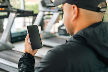 Young Athlete fitness Man Using smartphone in gym. Male Holding Cell Phone Fitness App