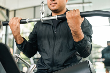 Guy weight training wearing sportswear. Asian man exercise indoor gym. Bodybuilder good health Young Fitness man pull up the machine bar in gym.