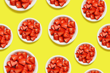 Sliced strawberries in a plate on a yellow background, top view, flat lay. Endless seamless background. Background with ripe strawberries