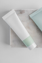 Cream tube on marble tray. Cosmetic skincare product blank plastic package. White unbranded lotion, balm, hand cream, toothpaste mockup. Sunscreen cream bottle with copy space