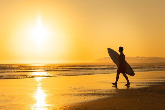 Silhouette of a man walking to the ocean at bright sunset