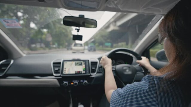 Side view of young Asian woman driving car through urban city. Women driving a car looking GPS map on screen in the car