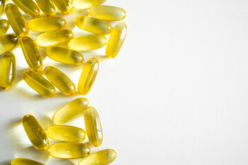 Oil filled capsules, softgel of food supplements. Fish oil, omega 3. Yellow softgels on white, copy space.