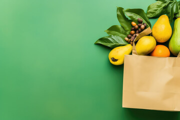 Top view of paper kraft bag with different fresh tropical fruits isolated on flat green background with copy space. Fresh fruit market banner template.