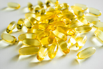 Golden color fish oil supplement in soft gel capsule on white background. Healthy vitamins, omega 3. Oil filled capsules of food supplements.