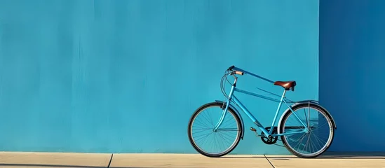 Deurstickers A high-quality photo of a bicycle is positioned against a blue wall, with empty space available © HN Works