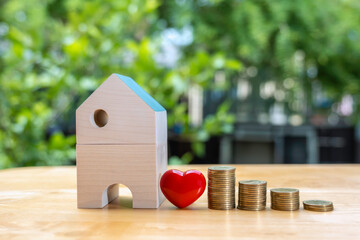 Coins stack near  the wooden home on wooden table to save the money invest for the future. Concept for loan, property ladder, financial, mortgage, real estate investment, taxes and bonus.