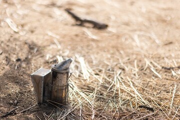Lit bee smoker on the ground making smoke