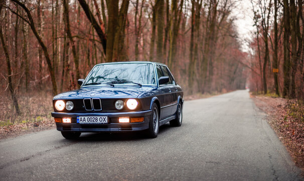 Dark blue BMW 5-series E28 standing still in autumn forest. Weekend drive on classic oldtimer car from the 1980s. Kyiv, Ukraine - November 26 2017.
