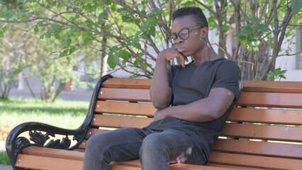 Fototapeta premium Sleeping Young African Man Sitting Outdoor on Bench