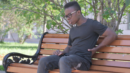 Obraz premium Young African Man Sitting Outdoor with Back Pain