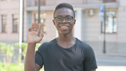 Outdoor Portrait of Young African Man Waving to Say Hello