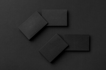 Mockup of four blank business card stacks at black textured background.