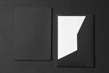 Corporate stationery set mockup. Closed and opened presentation folders with letterhead at black textured paper background.