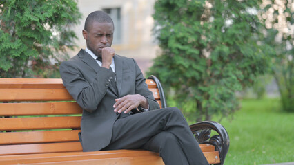 Obraz premium Coughing African Businessman Sitting Outdoor