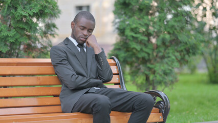 Obraz premium Sleeping African Businessman Sitting Outdoor on Bench