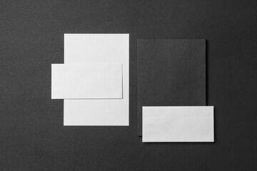 Corporate stationery set mockup. Two presentation folders and two letterheads at black textured paper background.