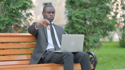 Thumbs Down by African Businessman Working on Laptop Outdoor