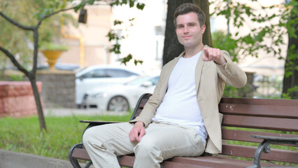 Fototapeta premium Casual Young Man Shaking Head in Acceptance while Sitting Outdoor
