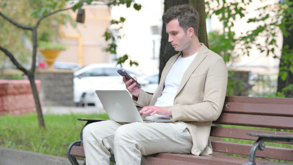 Casual Young Man Working on Laptop and Smartphone