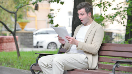 Casual Young Man Celebrating while Reading Documents Outdoor