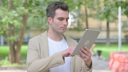 Casual Young Man using Tablet Outdoor