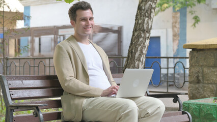 Thumbs Down by Young Man Working on Laptop Outdoor