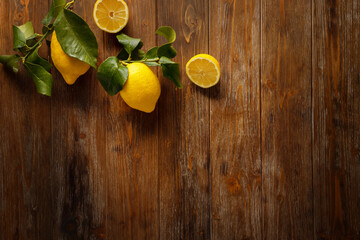 Composition of lemons with twigs and leaves on a wooden background