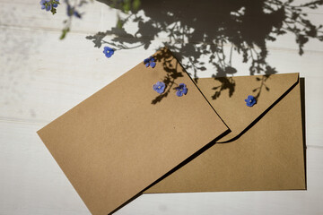 Postcard with envelope and bouquet of wildflowers on the table, flat lay