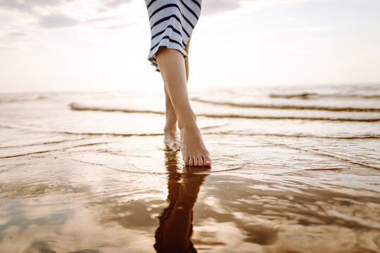 Leg of a young woman walking along the sea on a summer beach. Slim legs. The concept of vacation, travel, freedom.