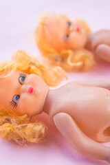 two old dolls on a pink surface side by side