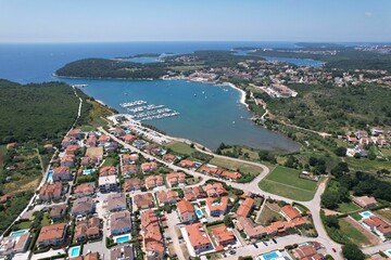 Aerial shot of a coastal town and marina with urban buildings and a port in Volme, Croatia