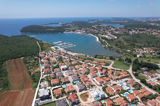Aerial shot of a coastal town and marina with urban buildings and a port in Volme, Croatia