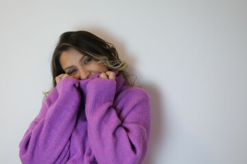 Young woman in a purple sweater posing hands placed gently on her face