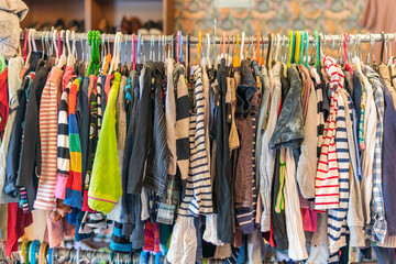 Sweden, Malmo – July 8, 2023: Different child, kid’s clothes on hangers and shelfs, hanging clothes in second hand store 