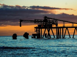 Obraz premium Pier stretching out into the tranquil sea at sunset