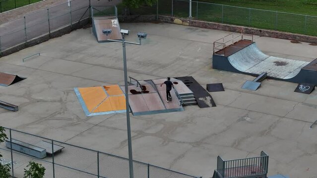 Aerial view of a young guy doing stunts with a skateboard at a skatepark