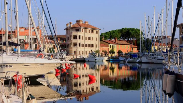 View of the quay of the canal with moored boats during the morning in Grado, a seaside resort, a wonderful, soothing atmosphere of an Italian picturesque town, Adriatic Sea, Italy