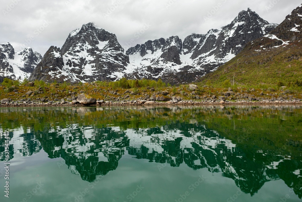 Sticker the mountains reflecting in water of a lake with snow covered peaks