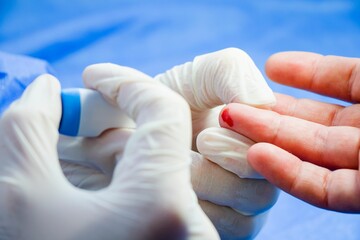 Close-up of a medical professional taking a blood sample from a patient's finger