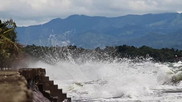 Violent waves surging and crashing against the boulevard in Dipolog CIty Philippines during a tropical typhoon and monsoon due to global warming and climate change