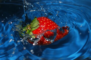 Fresh strawberry in a glass of water creating ripples