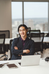 Asian businessman in stylish formal wear, black suit with crossed arms working at workplace