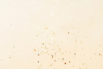 Shiny golden confetti on beige background, texture. Holidays concept