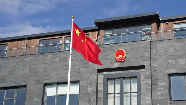 Waving Chinese flag and coat of arms at Chinese embassy building in Reykjavik, Iceland