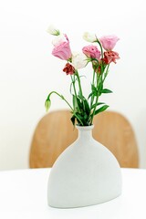 Elegant white ceramic vase filled with a vibrant bouquet of multicolored flowers